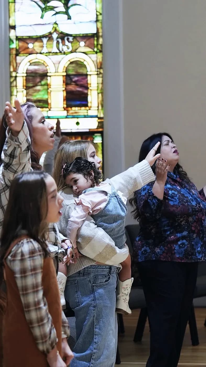 Families worshipping beside the stained glass windows at The Way Church