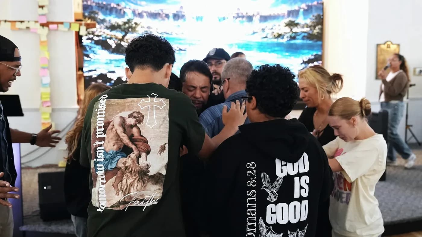 People gather and lay hands on a man in prayer at The Way Church