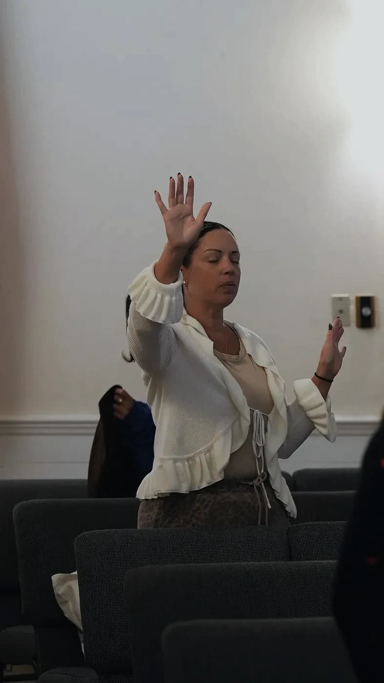 A woman worships with her eyes closed and hands raised
