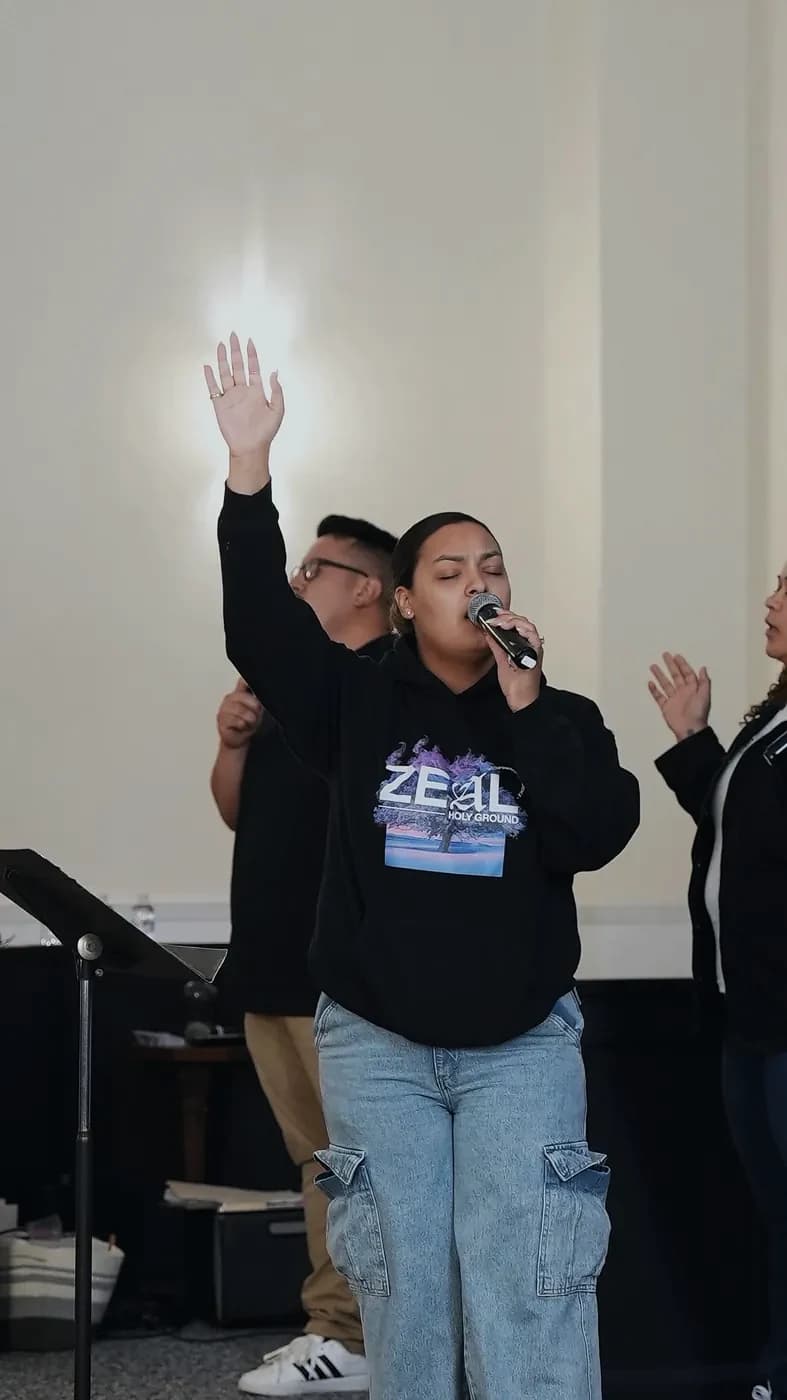 A worship leader sings with her hand raised during Sunday worship